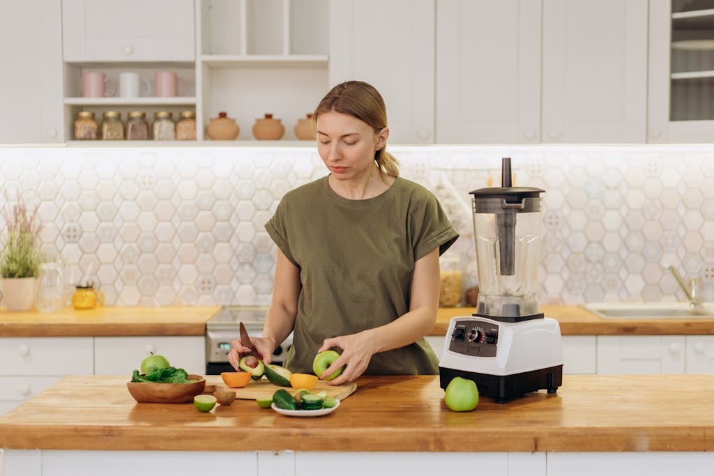 Woman in Green Crew Neck T-shirt Slicing Fruits